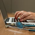 person sitting while using laptop computer and green stethoscope near